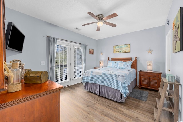 bedroom featuring visible vents, ceiling fan, a textured ceiling, wood finished floors, and access to outside