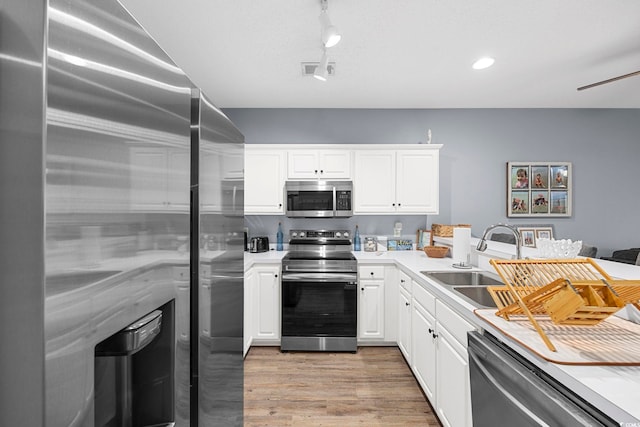 kitchen with stainless steel appliances, white cabinets, light countertops, and a sink