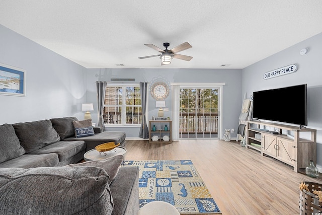 living room featuring a healthy amount of sunlight, light wood-style floors, a textured ceiling, and a ceiling fan