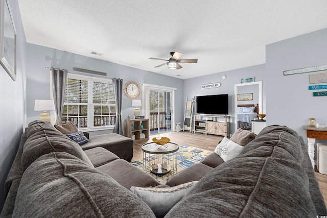 living room with visible vents, ceiling fan, a textured ceiling, and wood finished floors