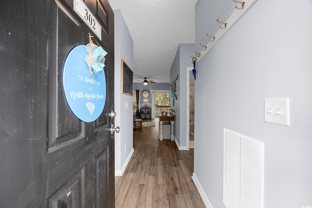 corridor featuring baseboards, visible vents, and wood finished floors