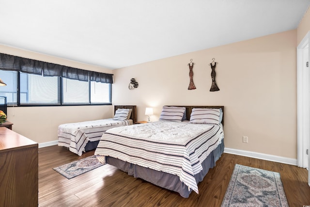 bedroom with dark wood-type flooring and baseboards