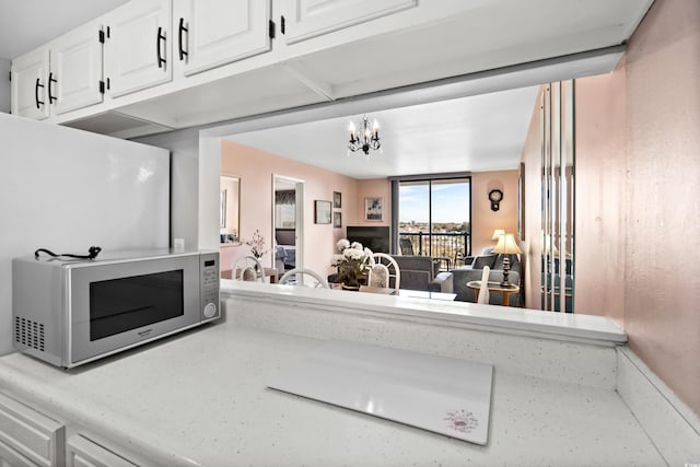 interior space with a chandelier, light countertops, white cabinets, and stainless steel microwave