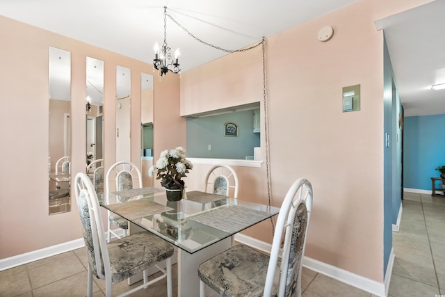 tiled dining space with a chandelier and baseboards