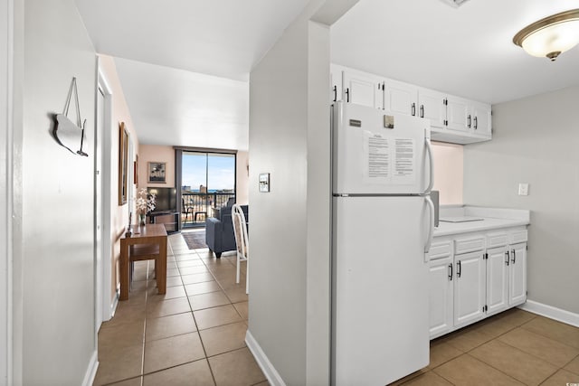 kitchen featuring freestanding refrigerator, light countertops, light tile patterned flooring, and white cabinetry