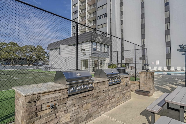 view of patio with a grill, fence, and an outdoor kitchen