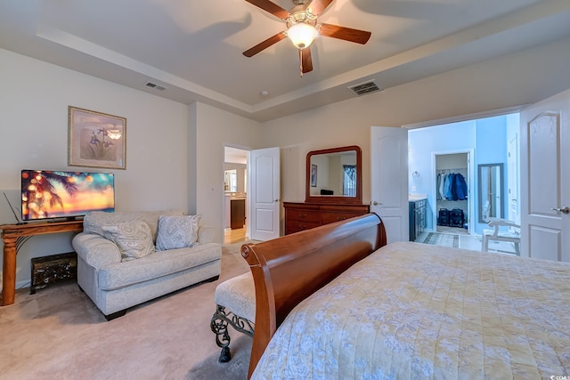 carpeted bedroom with ceiling fan, a spacious closet, visible vents, and a tray ceiling
