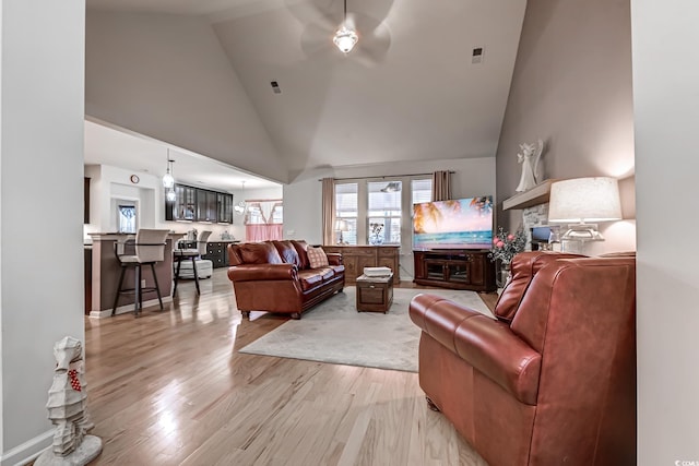 living room featuring high vaulted ceiling, visible vents, and light wood finished floors