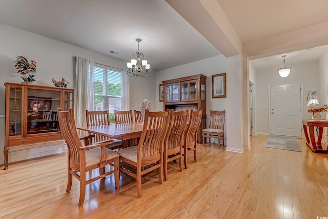 dining space with light wood-style floors, visible vents, baseboards, and an inviting chandelier