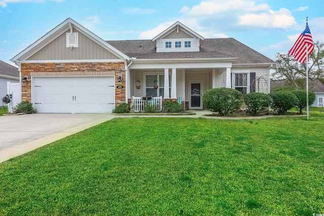 view of front of home featuring covered porch, driveway, a front yard, and a garage