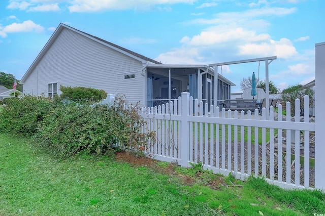 view of home's exterior with a yard, fence private yard, and a sunroom