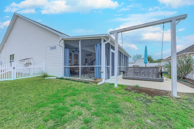 rear view of house with a lawn, a ceiling fan, a sunroom, a patio area, and fence