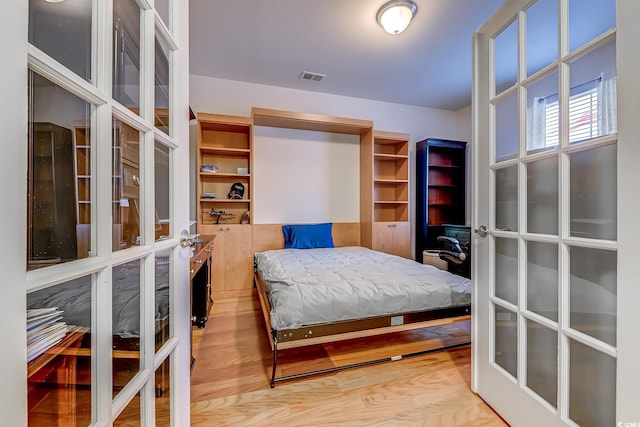 bedroom featuring french doors, visible vents, and light wood-style flooring