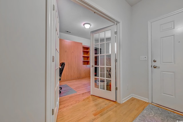 doorway with light wood finished floors, baseboards, visible vents, and french doors