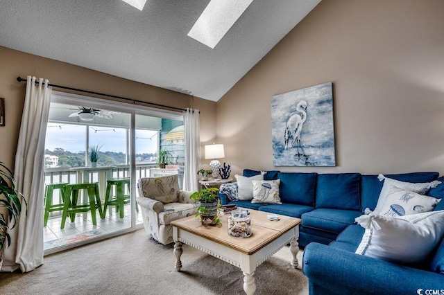 carpeted living area featuring vaulted ceiling with skylight and a textured ceiling