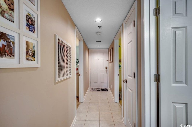 hall featuring light tile patterned floors, baseboards, a textured ceiling, and recessed lighting