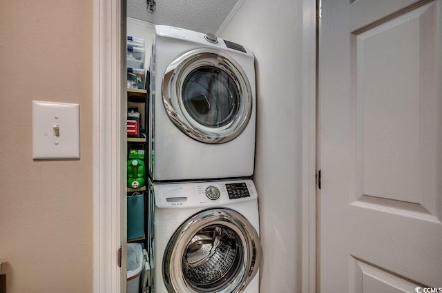 laundry area with stacked washer / dryer, laundry area, and a textured ceiling