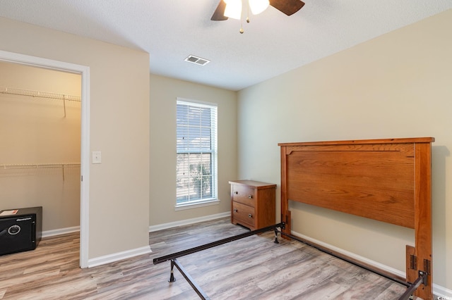 bedroom with a walk in closet, baseboards, visible vents, and light wood finished floors