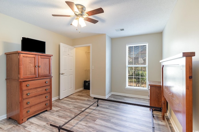 living area featuring light wood-style floors, visible vents, and a textured ceiling