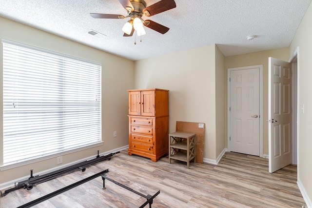 bedroom with light wood-type flooring, baseboards, visible vents, and a textured ceiling