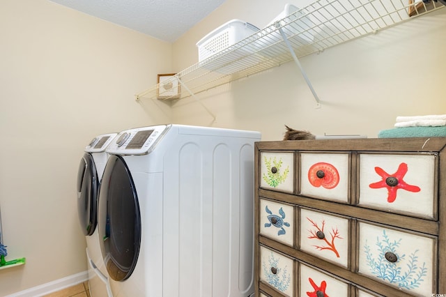 laundry room featuring a textured ceiling, laundry area, baseboards, tile patterned floors, and washer and clothes dryer