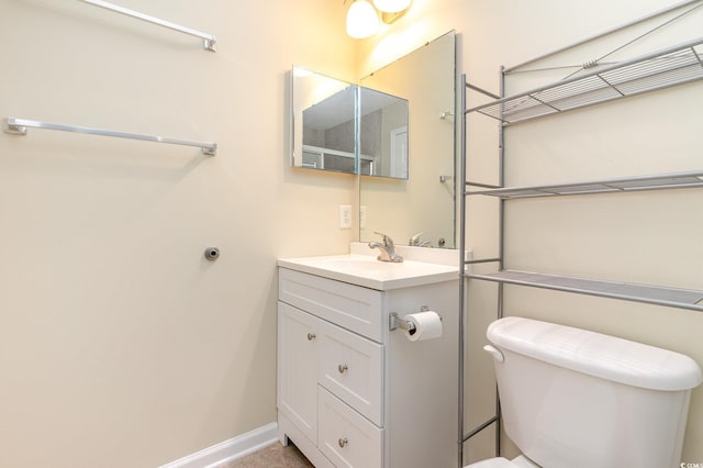 bathroom with baseboards, vanity, and toilet