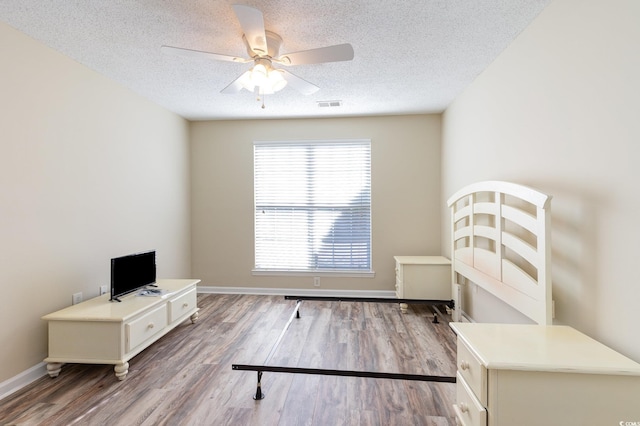 unfurnished bedroom with a textured ceiling, wood finished floors, visible vents, and baseboards