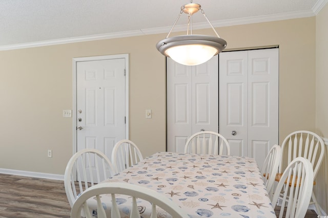 dining room featuring crown molding, a textured ceiling, baseboards, and wood finished floors