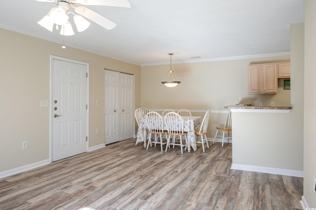 dining space featuring crown molding, wood finished floors, and baseboards