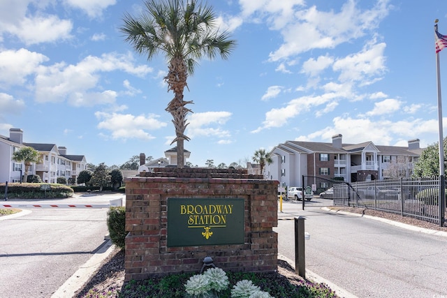 community / neighborhood sign featuring a residential view and fence