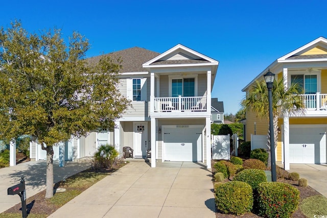 raised beach house with a balcony, driveway, a garage, and a shingled roof