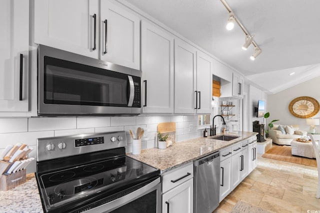 kitchen featuring a sink, tasteful backsplash, appliances with stainless steel finishes, white cabinets, and lofted ceiling