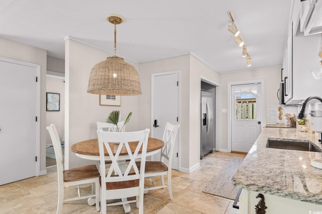 kitchen featuring light stone countertops, a sink, hanging light fixtures, appliances with stainless steel finishes, and white cabinetry