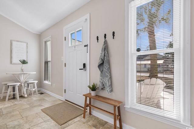 entryway featuring baseboards and lofted ceiling