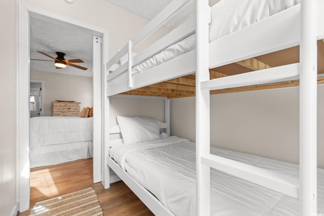 bedroom featuring a ceiling fan, wood finished floors, and a textured ceiling