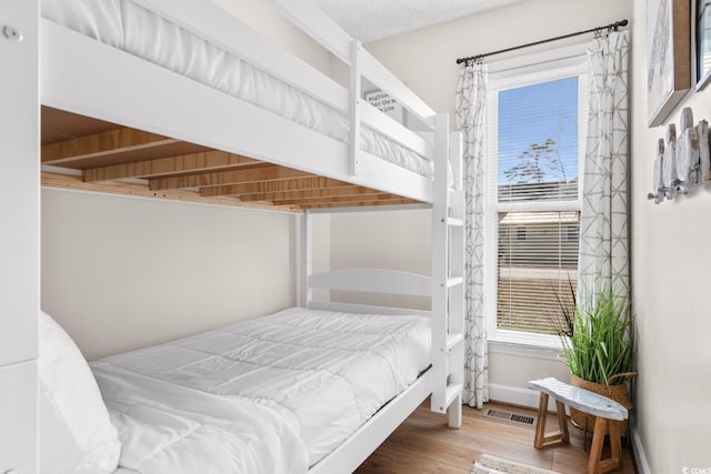 bedroom featuring visible vents, baseboards, and wood finished floors