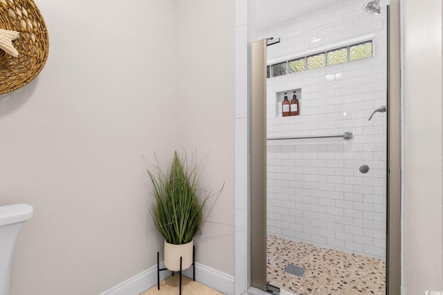 bathroom with baseboards and a shower stall