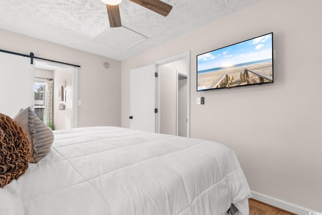 bedroom featuring baseboards, ceiling fan, attic access, wood finished floors, and a textured ceiling