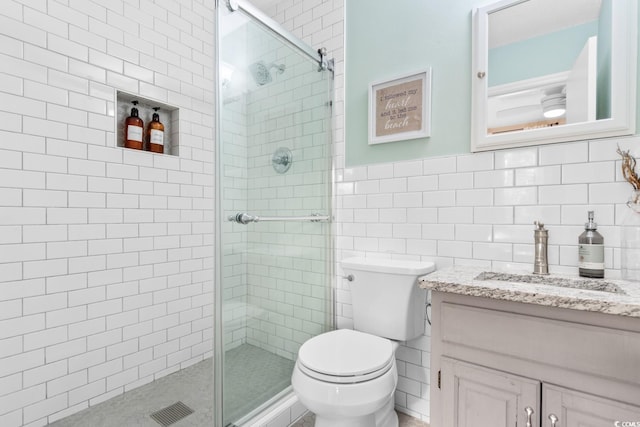 bathroom featuring toilet, a stall shower, a ceiling fan, tile walls, and vanity