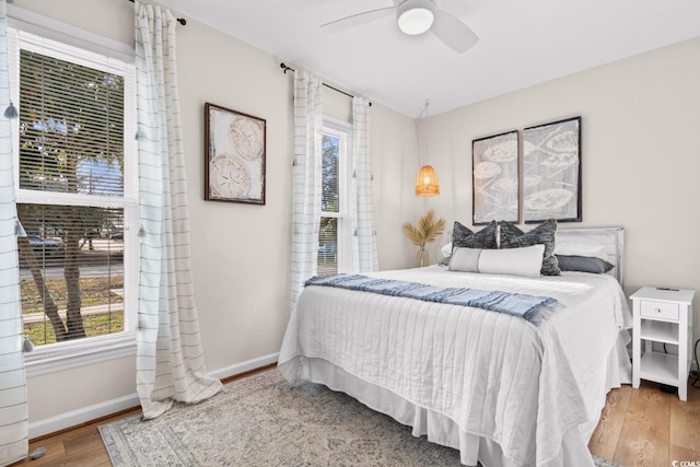 bedroom featuring baseboards, wood finished floors, and a ceiling fan