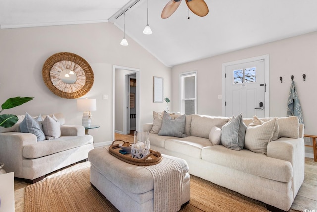 living area featuring vaulted ceiling, a ceiling fan, and baseboards