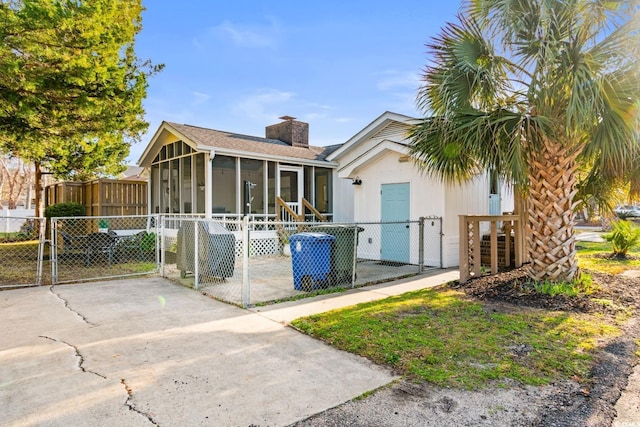 view of front facade with a sunroom, fence, a chimney, and a gate