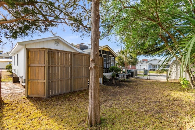 view of yard with a gate, fence, and a sunroom