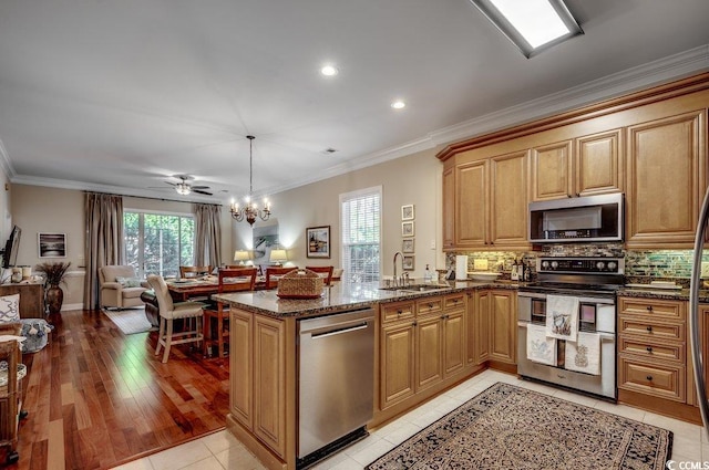 kitchen with open floor plan, appliances with stainless steel finishes, tasteful backsplash, dark stone countertops, and decorative light fixtures