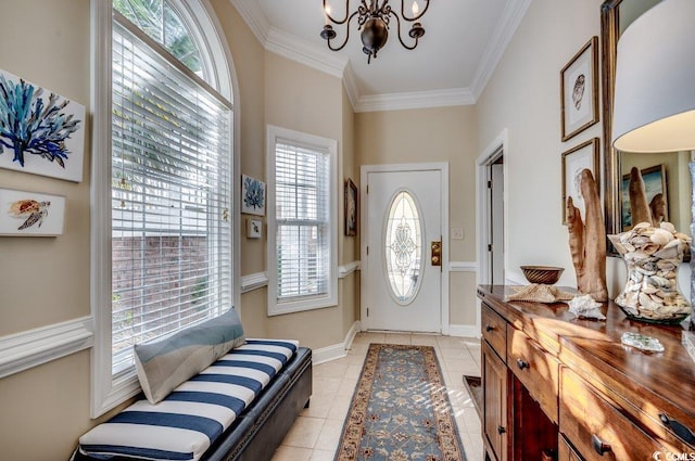 foyer with an inviting chandelier, baseboards, ornamental molding, and light tile patterned flooring