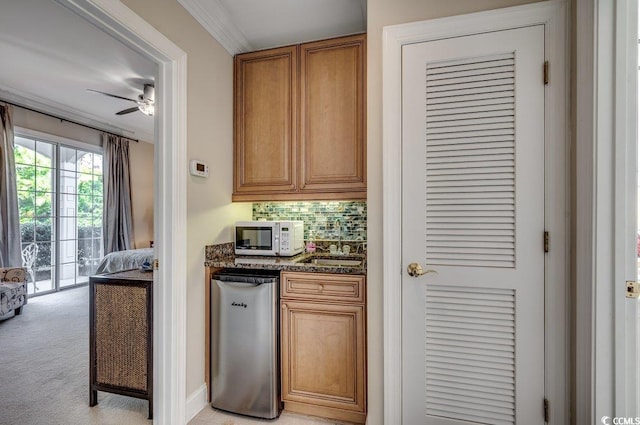 kitchen featuring light carpet, decorative backsplash, appliances with stainless steel finishes, brown cabinets, and a sink