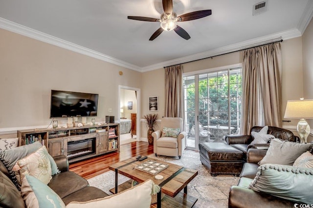 living area featuring light wood-type flooring, ceiling fan, visible vents, and crown molding