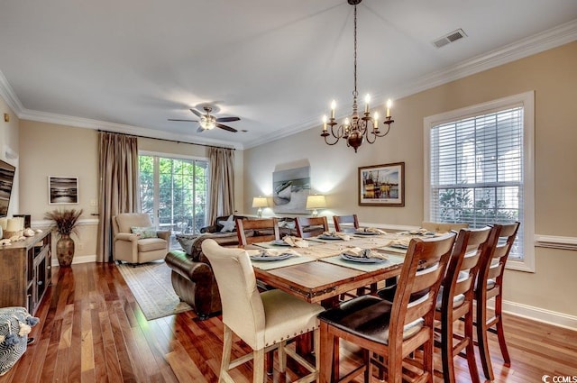 dining area featuring baseboards, wood finished floors, visible vents, and crown molding