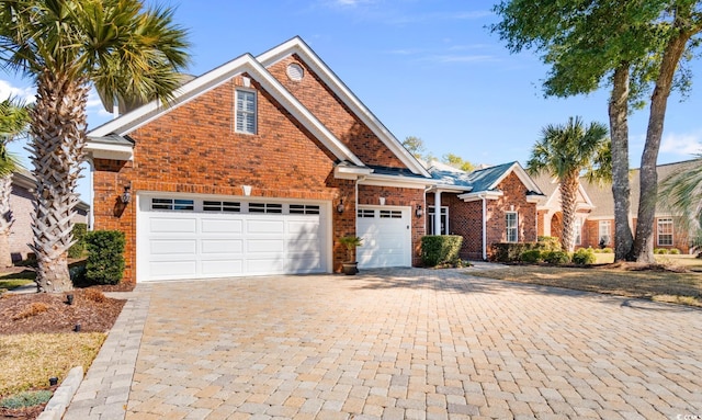 traditional-style home featuring brick siding, decorative driveway, and an attached garage