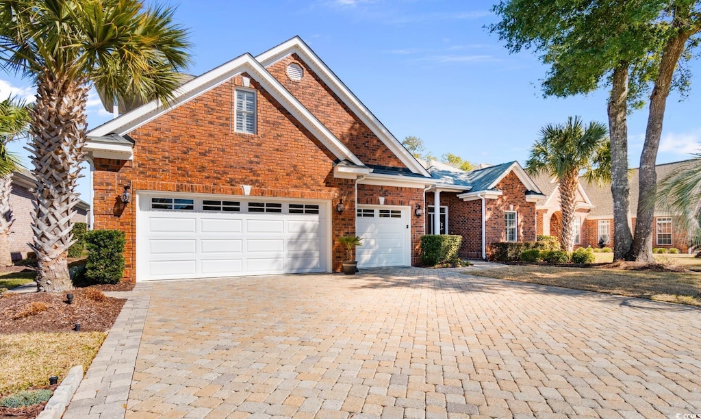 traditional-style home featuring brick siding, decorative driveway, and an attached garage